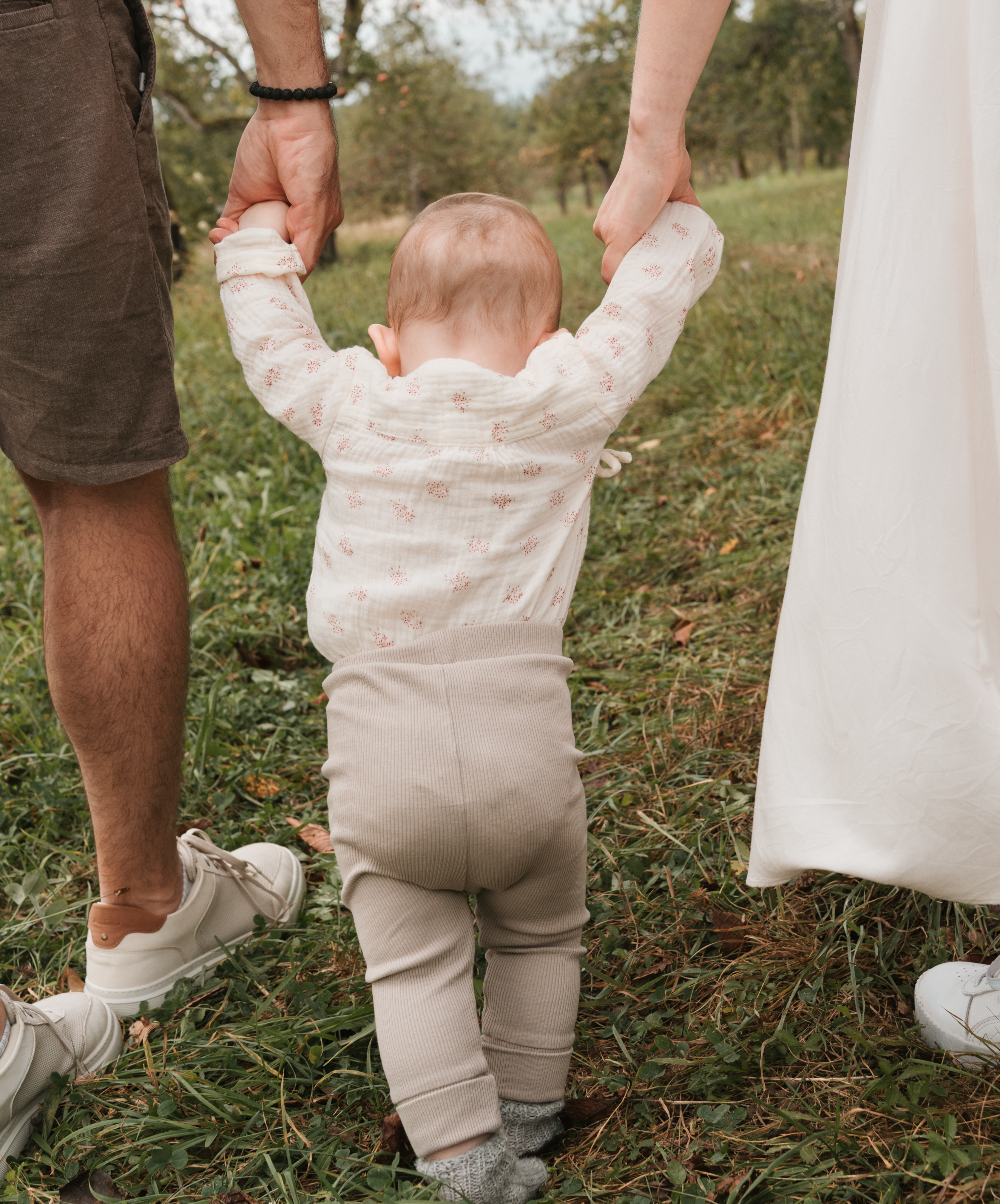 Foto von einem Baby, das beim Familien-Shooting von seinen Eltern festgehalten wird.
